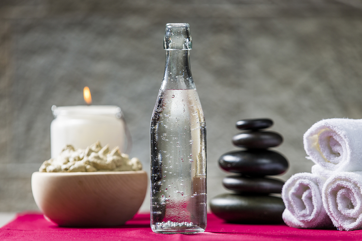 Sveče, steklenica mineralne vode, brisače in skleda s kremo