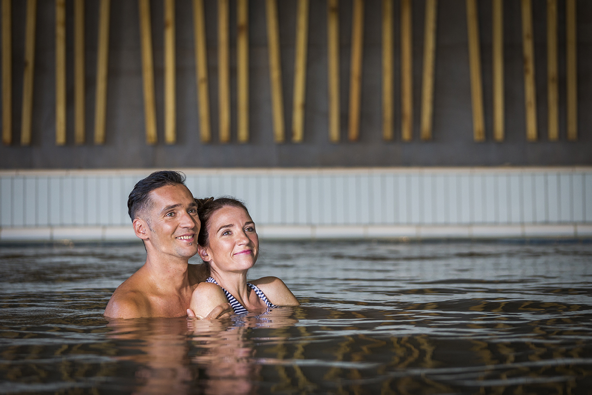 Moški in ženska se v notranjem bazenu objemata in zamišljeno gledata naprej