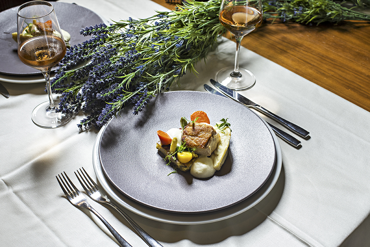 Dekorirana miza s prtom, dvema kozarcema alkoholne pijače in dvema krožnikoma privlačne jedi