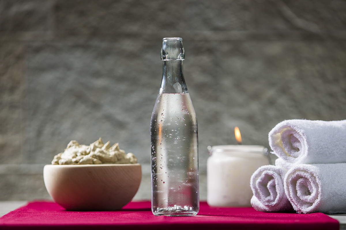 Sveče, steklenica mineralne vode, brisače in skleda s kremo